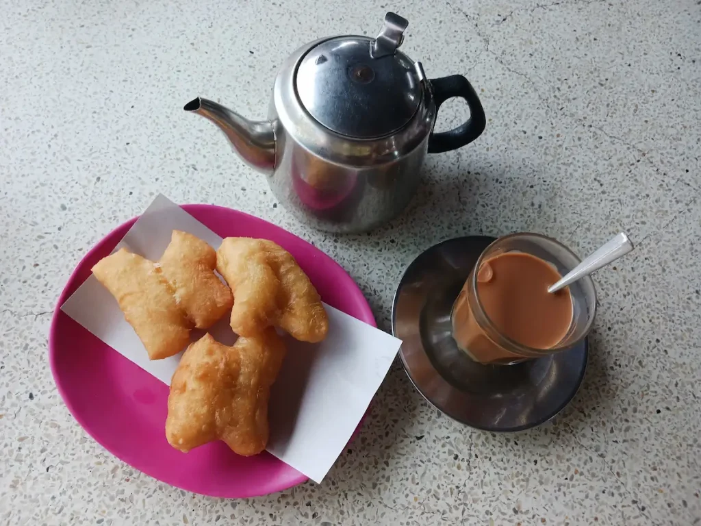 お皿に盛られたパトンコー三個とチャイ、お湯が入ったヤカン