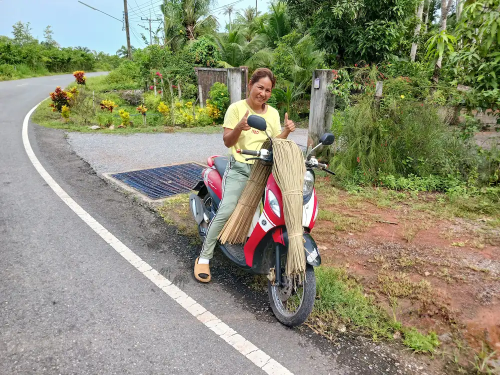 カチュー(水草の一種)の束を原付で運んでいる時に立ち止まり笑顔でサムズアップしてくれる地元の女性