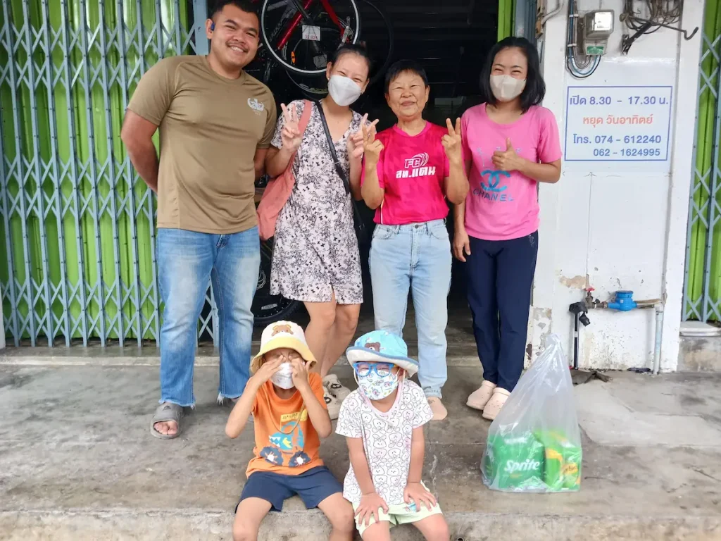 三世代の家族5人が自転車屋の前で笑顔でピースサインをしている