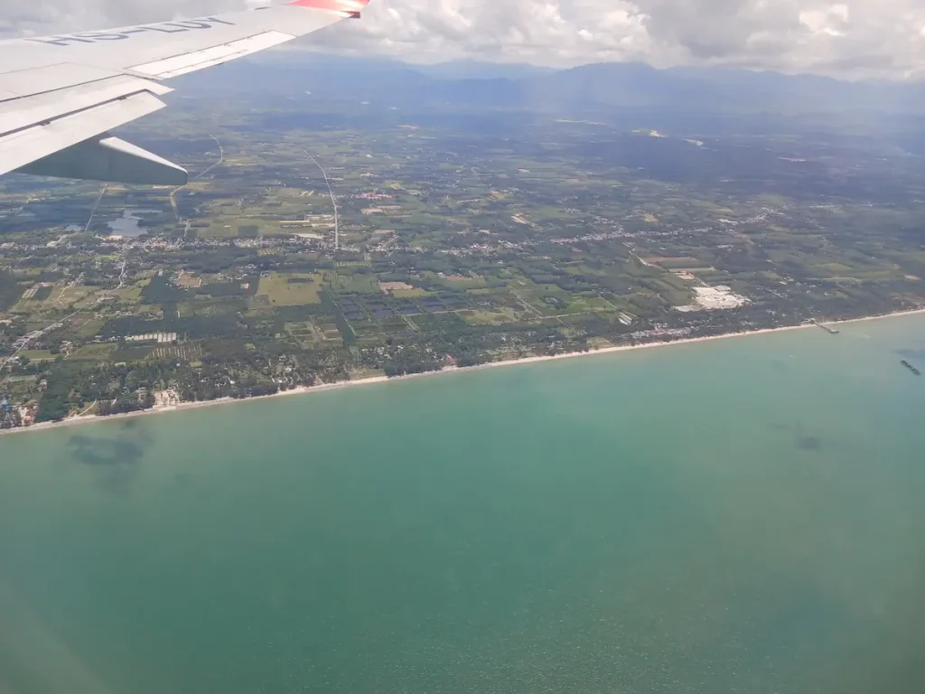 間もなく着陸する機内から見えるターコイズブルーの海と緑に囲まれた街並み