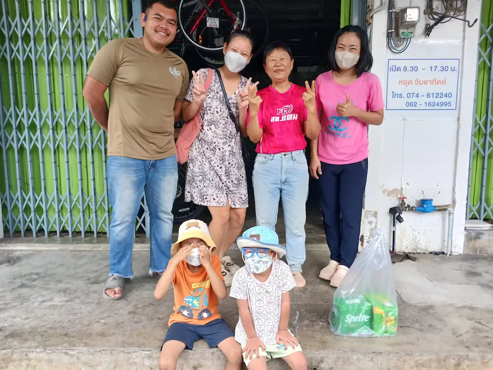 タイ南部の街パッタルンで三世代の家族5人が自転車屋の前で笑顔でピースサインをしている