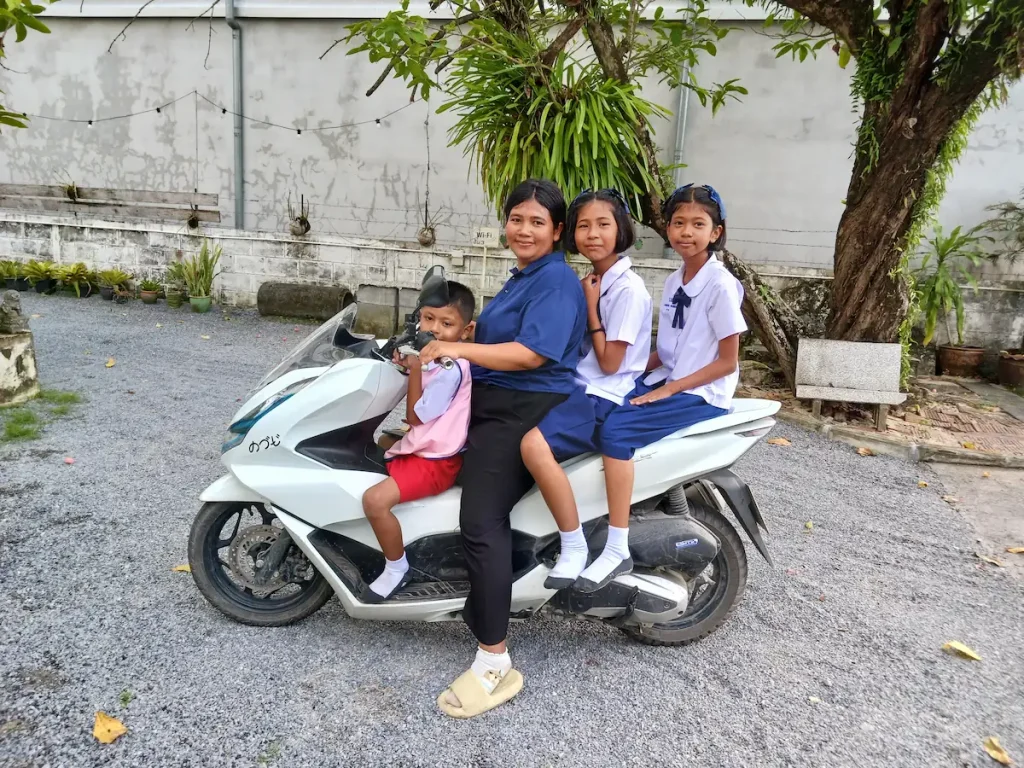 ノームスペースホステルの中庭でバイクに乗りカメラに向かって微笑む母と三人の子供