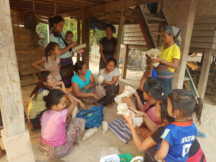 ラオス北部カム族の村で、葛の糸の束を手に持ち談笑するカム族の女性たち