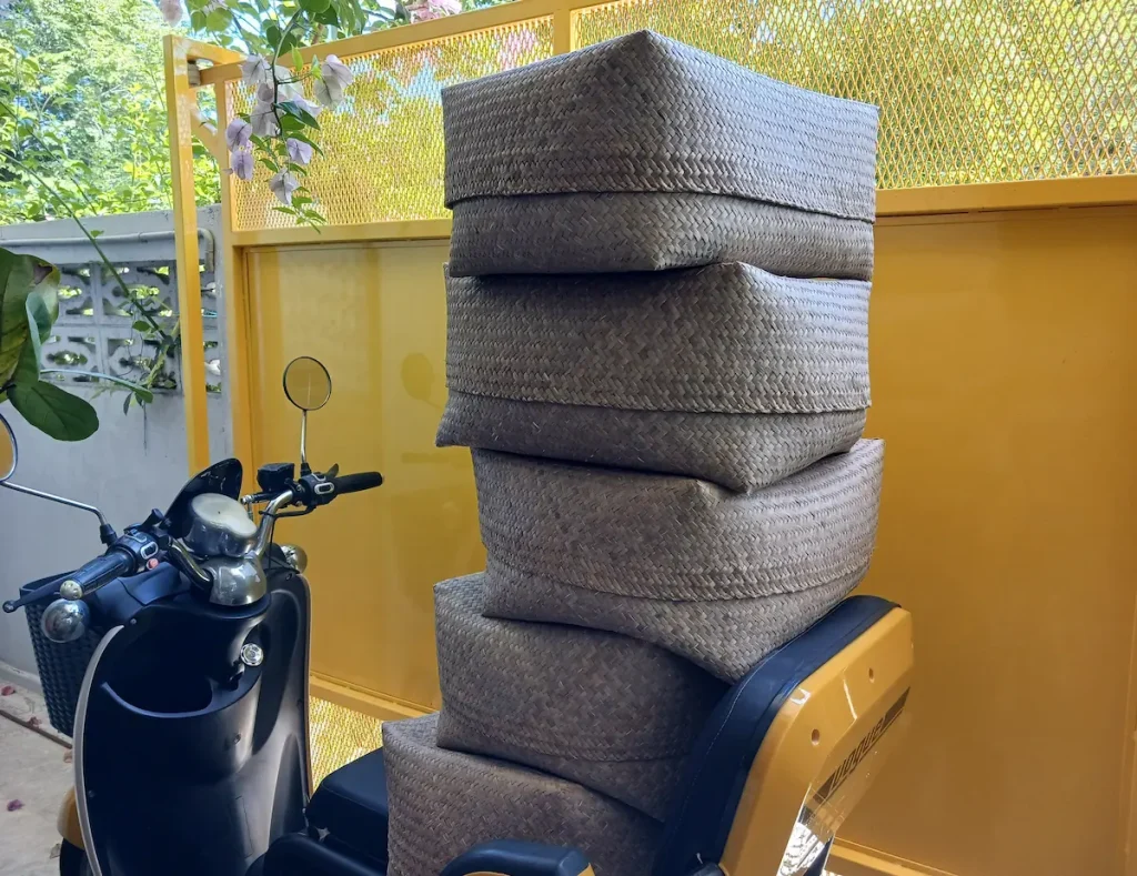 電動バイクの座席の上に積まれたナチュラルな雰囲気のカチュー(水草の一種)の収納ボックス