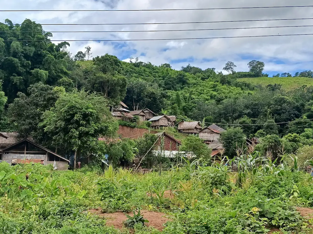 ラオス北部カム族の村の山の斜面に建つ木造の家々
