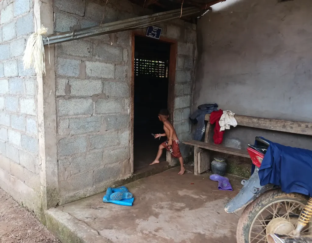 ラオス北部カム族の村でかくれんぼをする少年